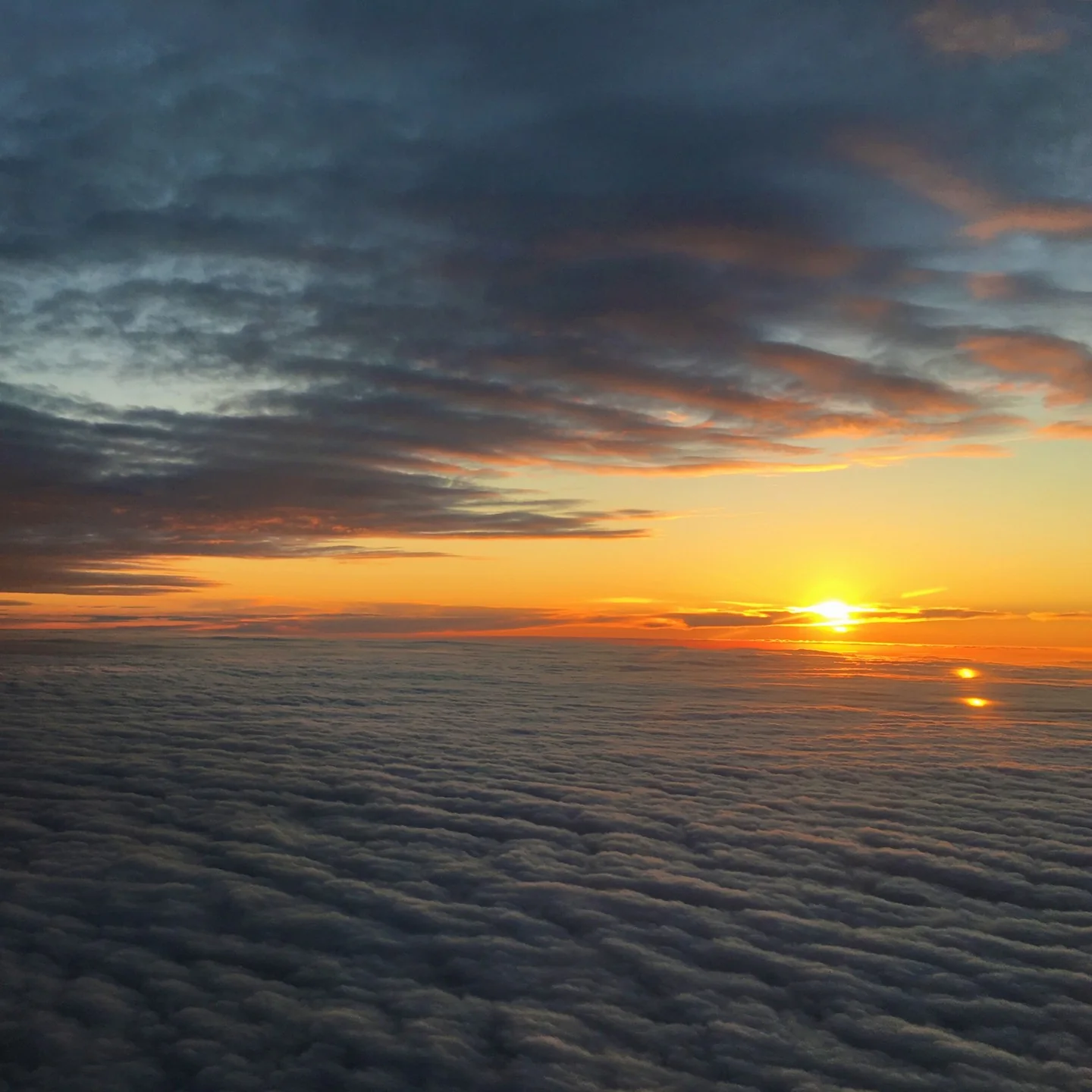 Sunset viewed from airplane window, between two layers of clouds.