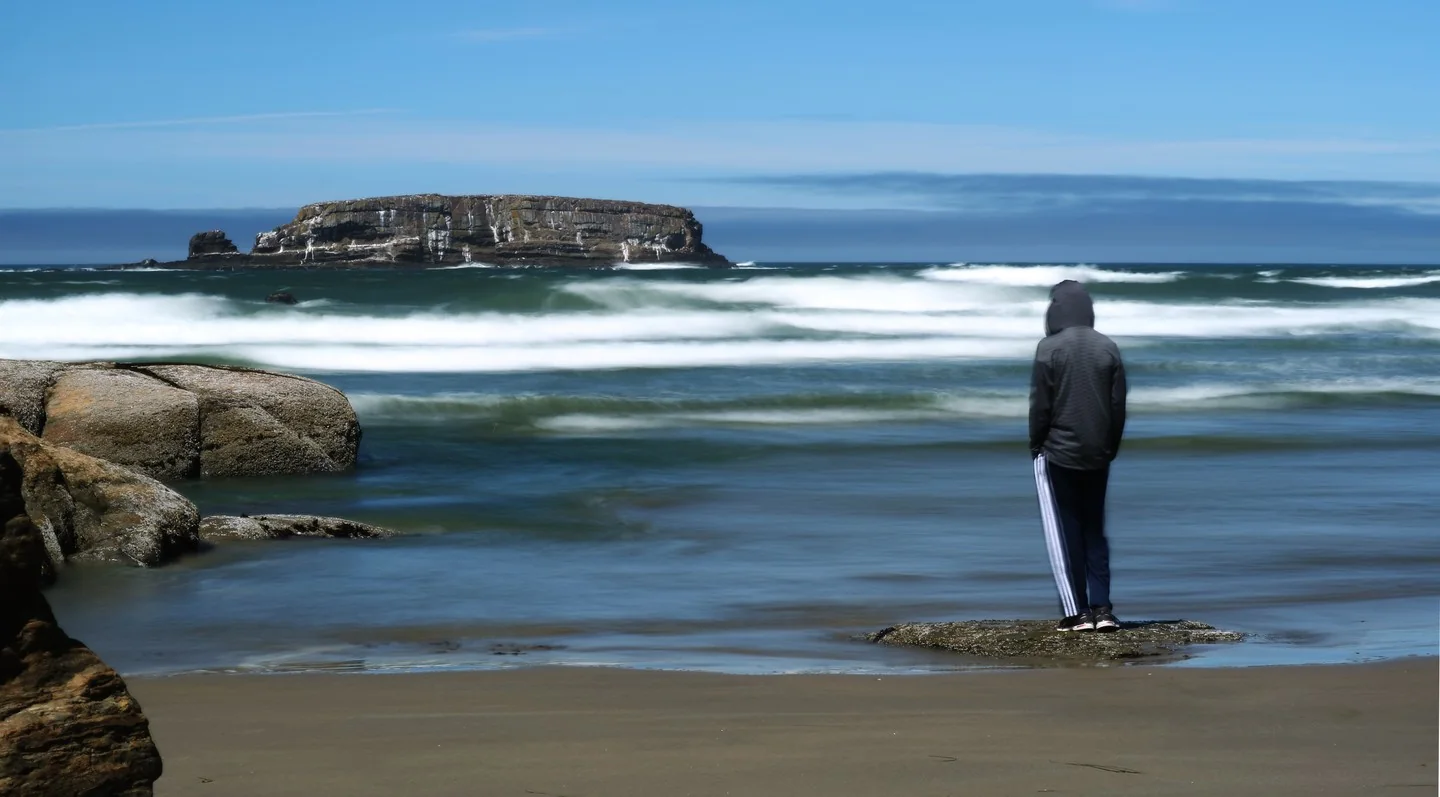 Person on shore looking at Otter Rock.