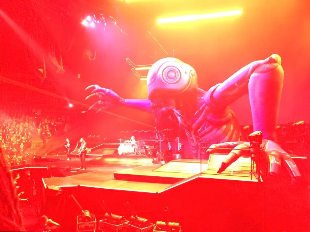 A giant skeleton behind a group of performers on stage. Everything is washed in red light.