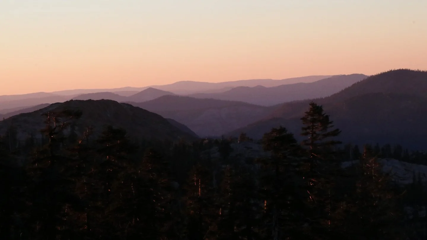 A picture of mountains silhouetted by the sunset.