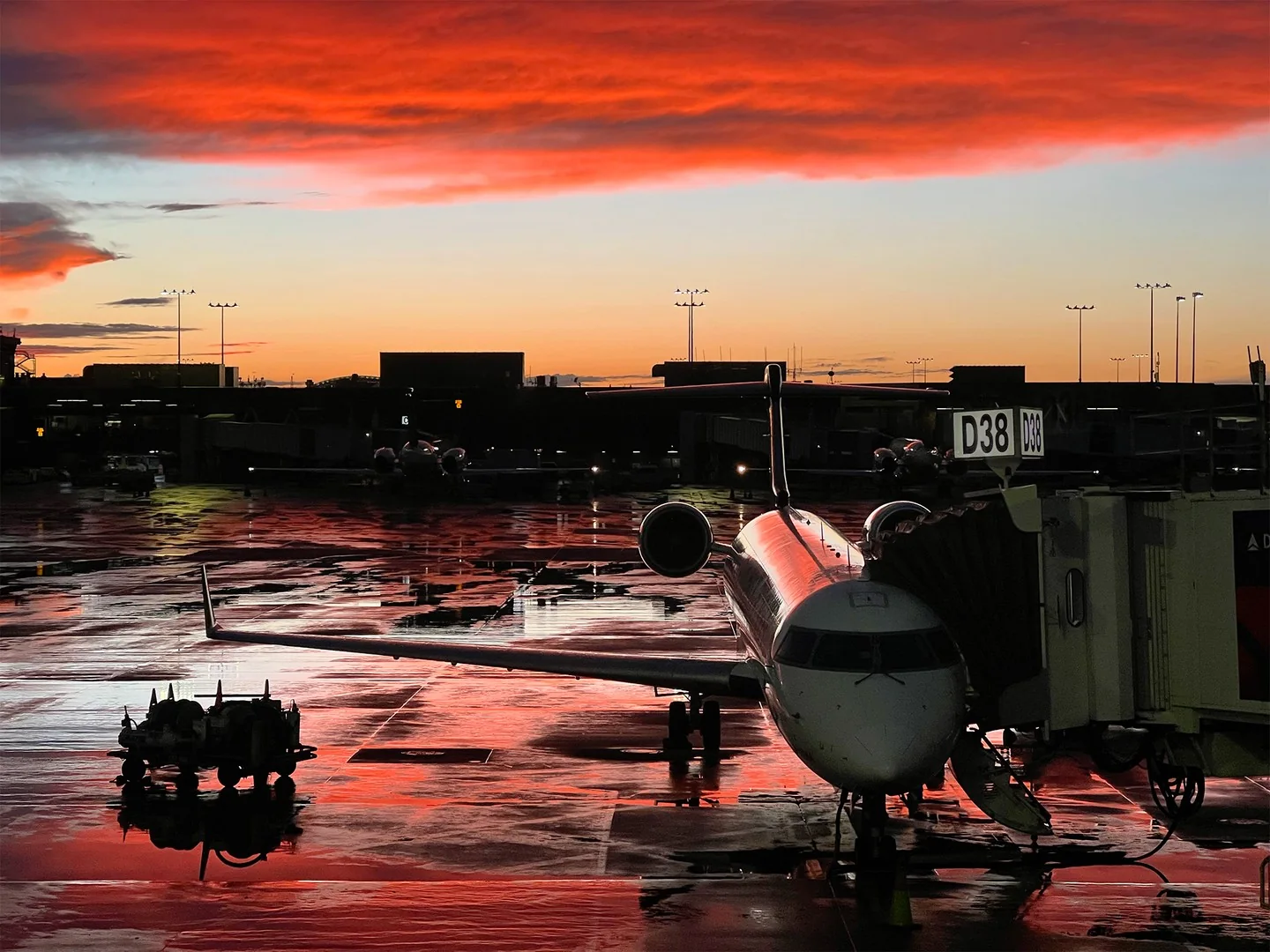 Plane at boarding gate after rain at sunset.