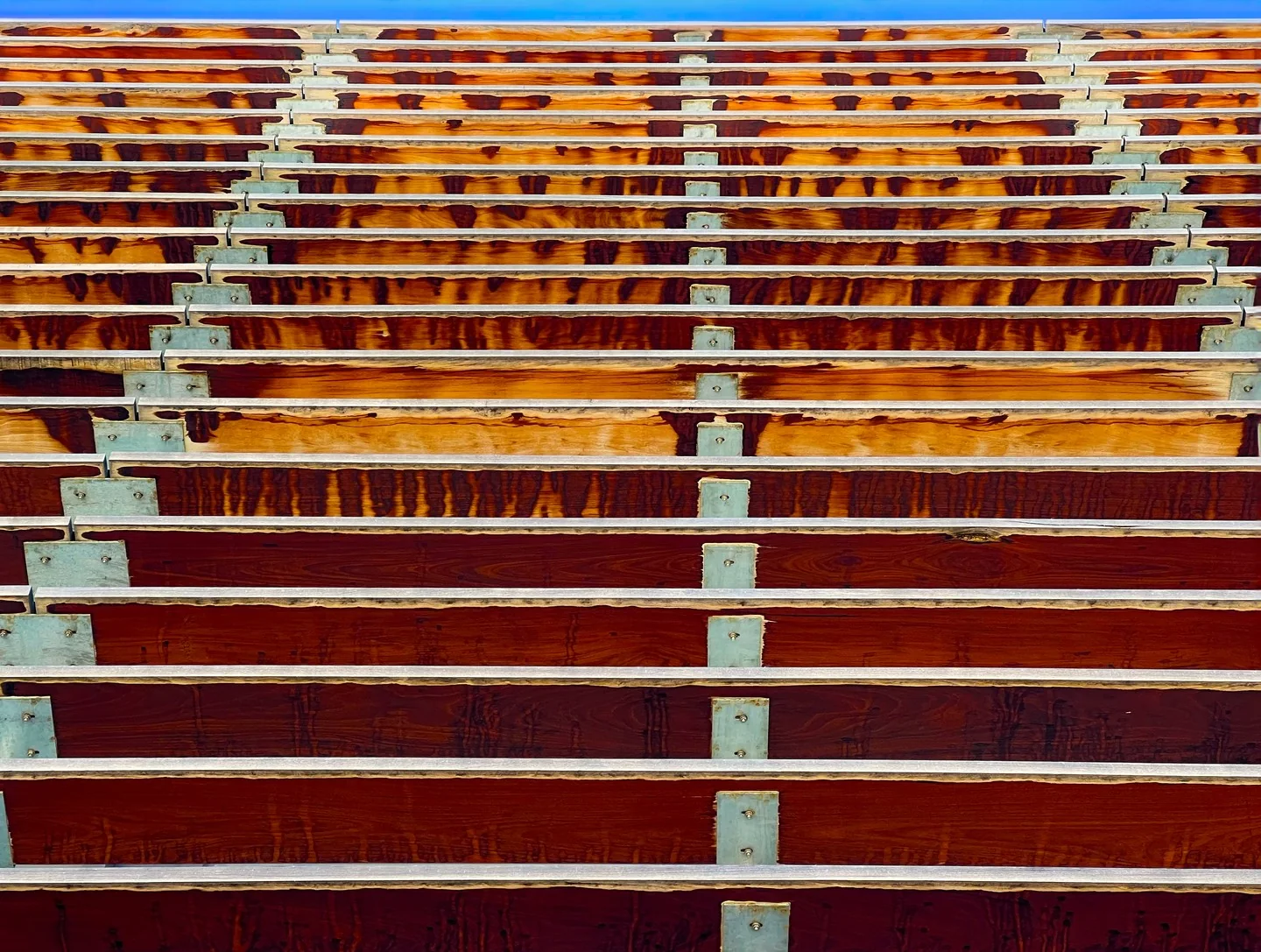 Wooden slats on the side of a building with a liver of sky above them.